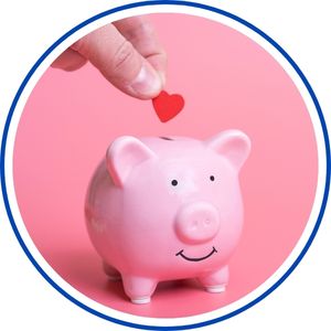 A white piggy bank with a smiling face on a pink background as a hand places a small red heart on top.