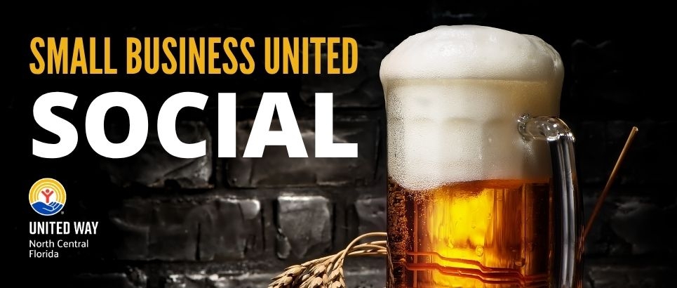 A foaming mug of beer sits on a wooden counter with a black brick backdrop.